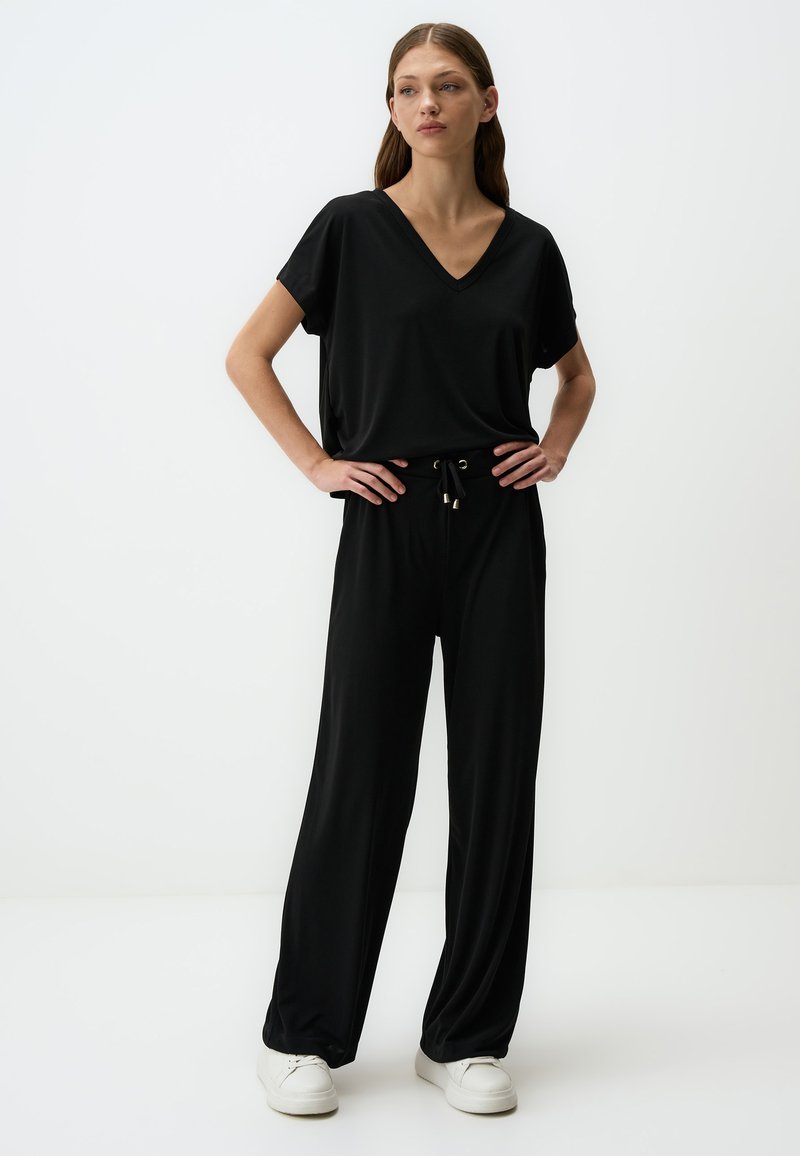 Zwart tweedelig outfit met een korte mouwen V-hals top en wijde broek met een elastische tailleband en trekkoord detail. Zachte stof.