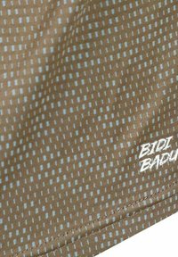Tela Bidi Badu con una base marrón y puntos geométricos en azul claro. Presenta una textura suave con bordes cosidos y un logotipo en la esquina.
