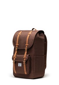 Brun tyg ryggsäck med läderremmar och gyllene spännen. Har en framficka och vadderad bakpanel för komfort.