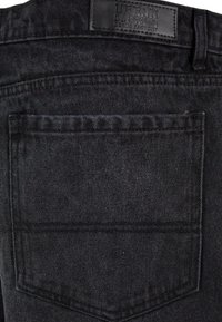 Black denim jeans with a leather brand tag. Features a back pocket with visible stitching and a textured fabric. Simple and functional design.