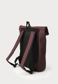 Rucksack mit maroonfarbener Außenseite, Details aus schwarzem Netzstoff, gepolsterten Trägern und Rollverschluss. Verfügt über eine strukturierte Oberfläche und ein minimalistisches Design.