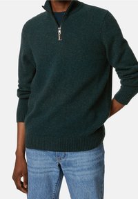 Donkergroene zip-neck trui gemaakt van een gestructureerde breistof. Voorzien van geribbelde manchetten en een zoom, met een zilveren rits en een hoge kraag.