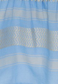 Světle modrá látka s horizontálními pruhy a cik-cak vzorem v krémové barvě. Měkká textura s nařaseným okrajem nahoře.