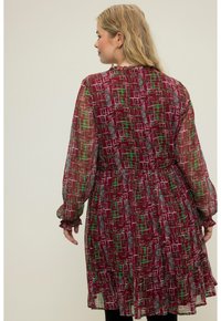 Doorzichtig, bordeauxrood jurk met een geometrisch patroon in wit en groen, met lange mouwen, een gathering in de taille en details van gerimpelde zoom.
