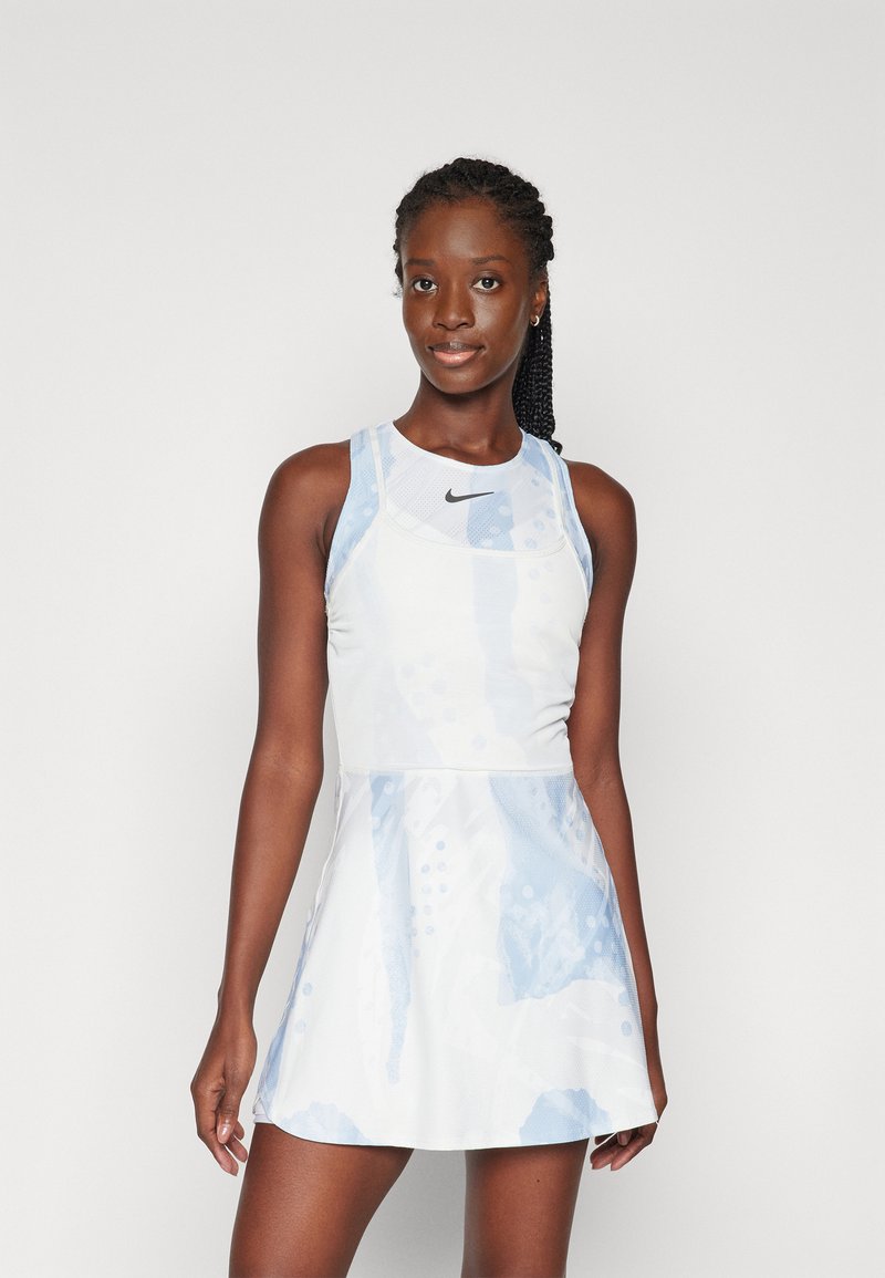 Bela športna obleka z jasno modrimi abstraktnimi vzorci, brezrokavni dizajn in okrogla ovratnika. Nike logotip na prsih, strukturirana tkanina.