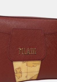 Clutch in pelle rossa testurizzata con logo dorato. Presenta una tasca anteriore con stampa mappa. Forma rettangolare compatta con linee pulite.