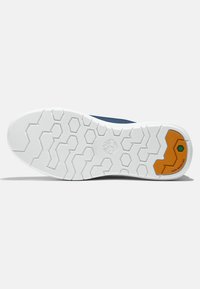 Suela de zapato con una base de goma blanca y un patrón de hexágonos, una sección superior azul y un acento naranja cerca del talón etiquetado como "NO MARCA".