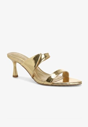 Złote metaliczne mule z odkrytym noskiem, dwoma paskami i smukłym, średniej wysokości obcasem na białym tle.