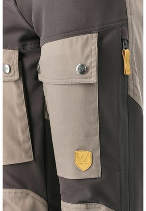 Cargo bukser i mørkegrå og beige stof, med flere lommer, sølv knaplukninger og et gult læderlogo.