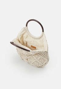 Sac fourre-tout macramé couleur crème avec poignées rondes en bois foncé et doublure en tissu beige avec poche zippée à l'intérieur.