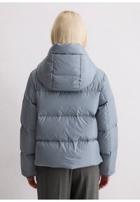 Hellgraue Pufferjacke mit Kapuze, ausgestattet mit einem gesteppten Design, glatter Textur und horizontalen Nähten für Isolation und Wärme.