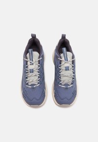 Niebieskie i szare buty sportowe z siateczkową cholewką, wyściełanym kołnierzem i kontrastującą beżową podeszwą. Posiadają wzór w kratkę oraz okrągłe sznurówki.