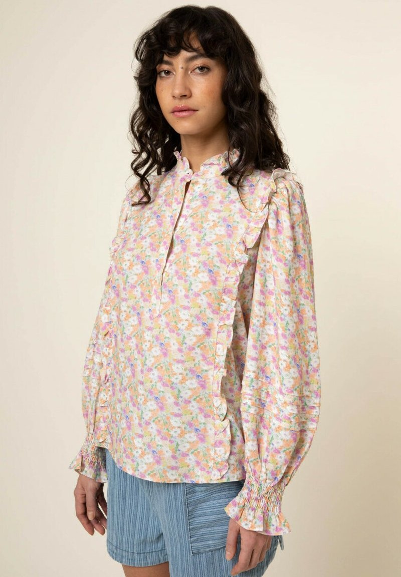 Bluse mit floralem Muster in Pastellfarben, Rüschenausschnitt, langen Ärmeln mit elastischen Bündchen und einer Knopfleiste auf der Vorderseite.