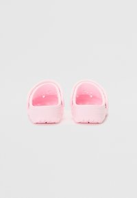Rozā koka kurpes ar gludu, noapaļotu dizainu un izgriezumiem ventilācijai. Materiāls ir viegls un gumijveidīgs, ar fakturētu zoli.