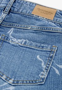 Lichtblauwe spijkerbroek met een vervaagde wassing, oranje stiksel en een klein achterzakje met een leren logo patch aan de tailleband.