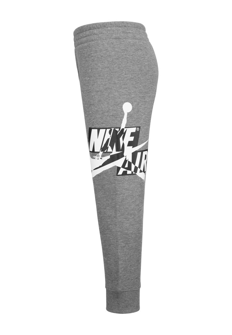 Szare tapered spodnie dresowe z elastycznym paskiem w talii i mankietami, z dużym białym logo Nike Air oraz sylwetką Jumpmana po bokach.