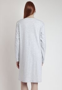 Vestido gris de manga larga hecho de una suave mezcla de algodón, con un cuello redondo y un corte relajado, rematado a mitad del muslo con detalles de costura sencilla.