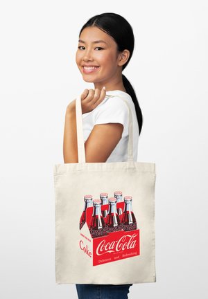 Borsa a rete in beige con grafica rossa della Coca-Cola, che presenta bottiglie di vetro e la scritta "Deliziosa e Rinfrescante".