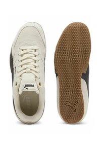 Zapatilla de ante crema con acentos negros, cierre de cordones y suela exterior de goma texturizada con un agarre estampado. Logo de Puma en la lengüeta.