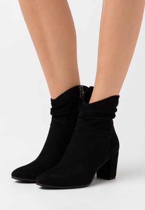 Black suede ankle boots with a slouched upper, pointed toe, and a block heel. Features a side zipper for easy wear.