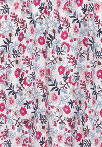 Bloemstof met een witte achtergrond en roze, rode en blauwe bloemen, verweven met groene bladeren en gedetailleerde takken.