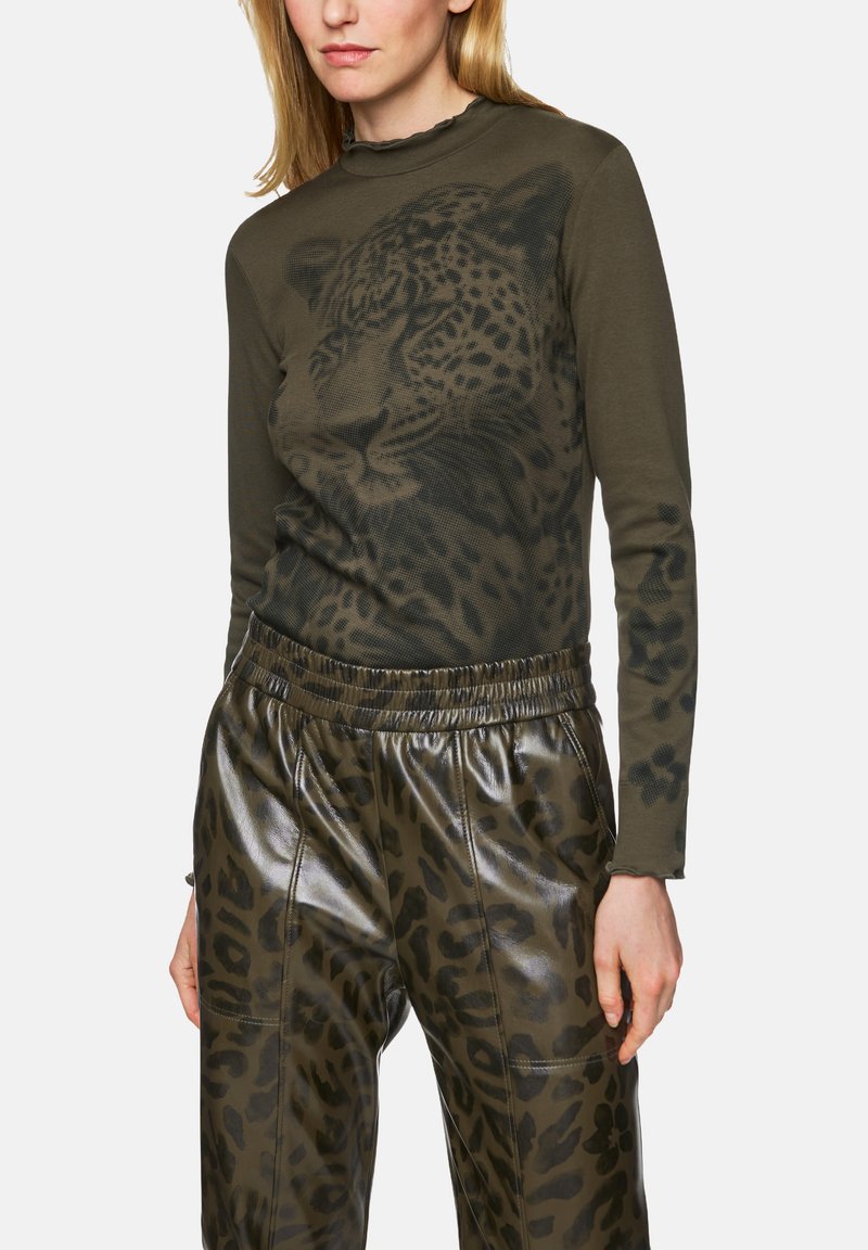 Long-sleeve, olive-green top with a leopard print graphic, paired with black, shiny leather pants featuring a matching leopard pattern.