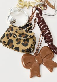 Mini bolsa de pele sintética estampada de leopardo com pendente de laço castanho, ferragens prateadas e alça trançada cor de vinho com contas e porta-chaves.