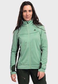 Hellgrüne Fleecejacke mit hohem Kragen, schwarzen Akzenten und Seitentaschen, ausgestattet mit einem Reißverschluss und strukturiertem Stoff.