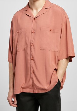 Camisa de manga corta en color coral, confeccionada con un tejido ligero, que cuenta con dos bolsillos en el pecho, un cuello con notch y cierres de botón.