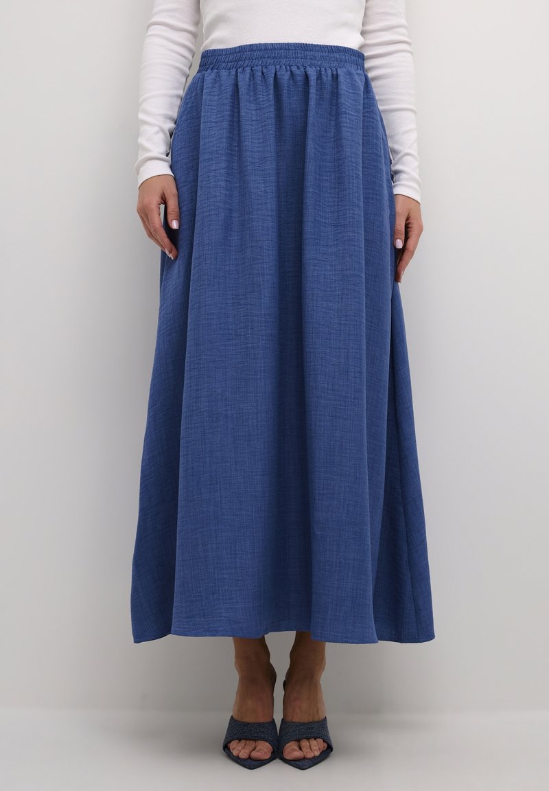 Blå, lang maxi nederdel lavet af tekstureret stof med elastisk talje, parret med åbne blå hæle.