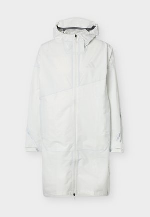 Abrigo impermeable largo y blanco con capucha, cremallera frontal, detalles reflectantes en las mangas y diseño hasta la altura de las rodillas, extendido sobre un fondo claro.