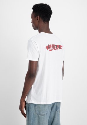 Hvid t-shirt med korte ærmer, der har et rødt og sort grafisk design på ryggen. Lavet af blødt bomuldsstof med rund halsudskæring.