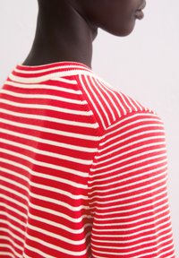 Rot-weiß gestreifter Pullover mit Rundhalsausschnitt, der eine weiche Textur und eine taillierte Form zeigt. Die Streifen sind gleichmäßig über den Stoff verteilt.