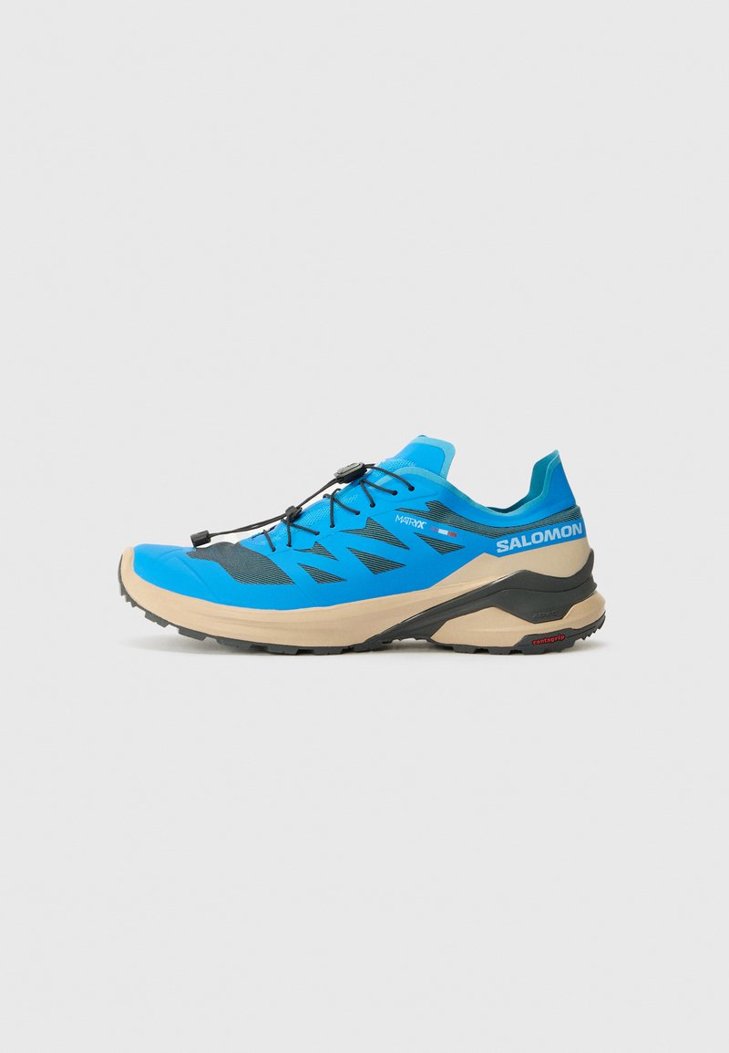 Chaussure de trail running bleue avec une tige en mesh respirant, accents noirs, bout arrondi et une semelle intermédiaire beige épaisse. Équipée de lacets réglables.
