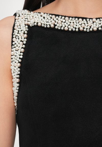 Svart klänning med ett slätt, texturerat tyg och en urringning prydd med kluster av pärlliknande pärlor och strass.