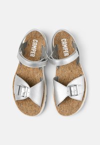 Silver sandals with cork footbeds, featuring a wide strap with a buckle and additional ankle straps for support.