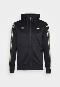 Černá mikina na zip z měkké látky, s nastavitelnou kapucí, neonově zelenými akcenty na rukávech a logem na hrudi. Dvě přední kapsy.