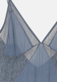 Camisole en dentelle bleue avec un décolleté en V, ornée de détails en dentelle florale transparente et d'un tissu texturé. Bretelles ajustables incluses.