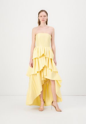 Gele strapless jurk met gelaagde ruches, hoge-lage zoom en een soepele stoftextuur. Versterkt met subtiele drapeerdetails.