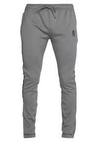 Szare sportowe spodnie o dopasowanym kroju, z elastycznym pasem, sznurkiem do wiązania i czarnymi paskami po bokach. Na górnej części nogawki znajduje się małe czarne logo.