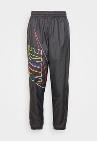 Svarta nylonbyxor med elastisk midja och mudd, med en stor flermönstrad broderad "NIKE"-logotyp på vänster ben.