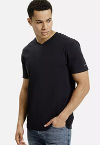 Czarny t-shirt z dekoltem w serek, wykonany z miękkiego materiału z krótkimi rękawami. Charakteryzuje się luźnym krojem oraz subtelnym detalem logo na lewym rękawie.