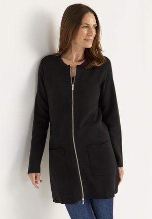 Svart lång cardigan med dragkedja framtill, två framfickor och rund halsringning. Tyget ser slätt och strukturerat ut.