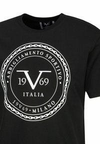 Schwarzes Baumwoll-T-Shirt mit einem großen weißen kreisförmigen Logo mit Ketten, dem Text "ABBIGLIAMENTO SPORTIVO ITALIA 1969 MILANO" und einem Rundhalsausschnitt.