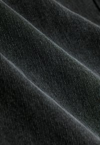 Tmavosivá tkanina s rebrovanou textúrou, zobrazujúca diagonálne čiary a mäkký, mierne reflexný povrch. Pružná a hladká.