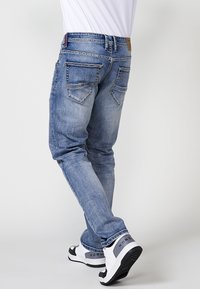Lyseblå denimjeans med slim fit, fem lommer og slidte detaljer. Sammen med hvide og sorte sneakers med et markant design.