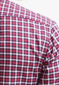 Rood en marineblauw geruit overhemd met een klassieke ruitpatroon en witte accenten, gemaakt van geweven stof met een gladde textuur.