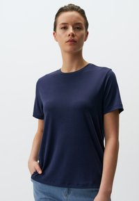 Navyblauw T-shirt met korte mouwen, gemaakt van gladde, lichtgewicht stof. Kenmerkt zich door een ronde halslijn en een losse pasvorm, gestoken in lichtblauwe jeans.
