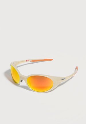 Beige sportsolbriller med oransje reflekterende ovale linser og oransje detaljer på stengene, vist på en hvit bakgrunn.