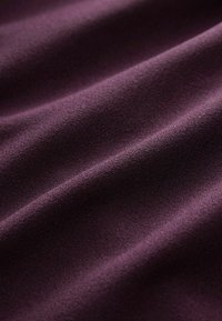 Zachte, gestructureerde stof in diep paars, met subtiele golven en een gladde afwerking, ideaal voor kleding of stoffering.